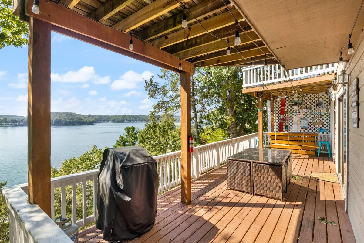 A relaxed social scene on a wooden deck with comfy outdoor furniture, a grill for barbecuing, and broad lake vistas. The mood is inviting and social, ideal for sunset gatherings or starlit evenings spent enjoying the outdoors.