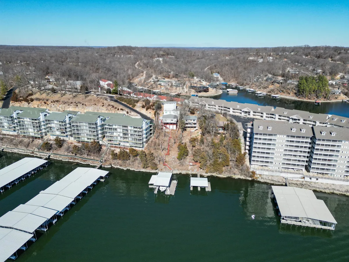 A lakeside dock with waterfront buildings and a marina in the background, set amid a natural landscape. The scene includes access for boating, fishing, and hiking, highlighting the property's connectivity to classic lake activities and the greater neighborhood.