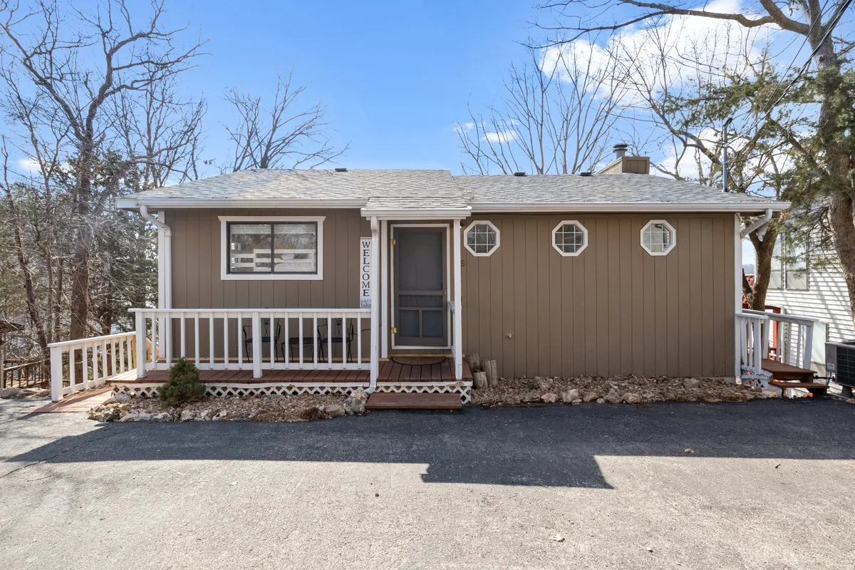 A welcoming front porch with a prominent welcome sign, round windows, comfortable seating, and tasteful landscaping. The image conveys a sense of hospitality and first impressions of arrival.