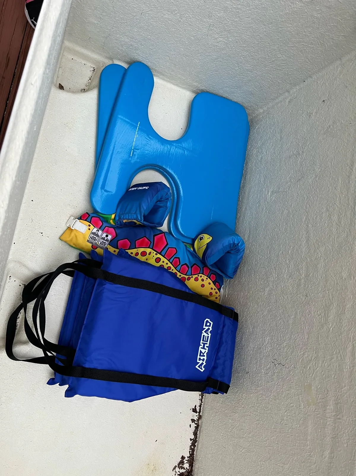 A collection of floaties and water toys—such as a blue floating device, colorful inflatable arm floats, and a blue bag—signaling playful water activities, family fun, and water safety.