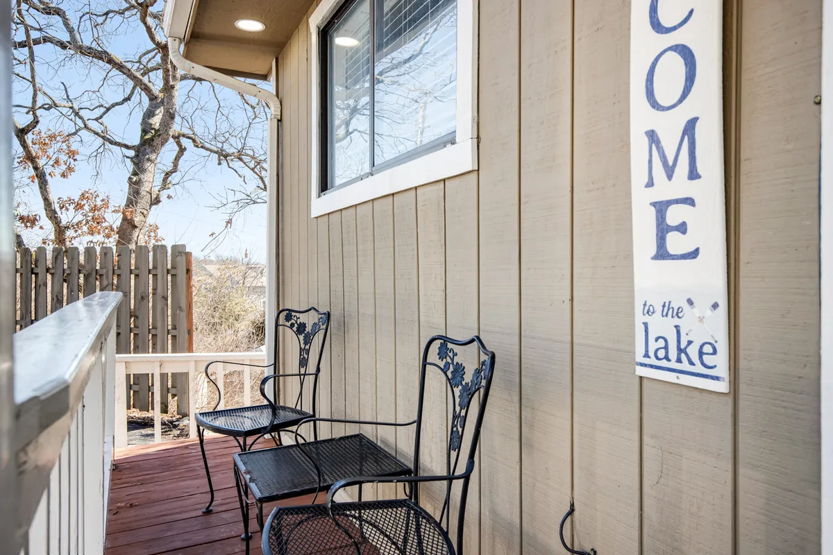 This image features a welcoming outdoor space with a visible 'welcome' sign, comfortable chairs, and a clear view of the lake beyond. The scene captures the inviting atmosphere of the property and its direct connection to lakeside relaxation and outdoor enjoyment.