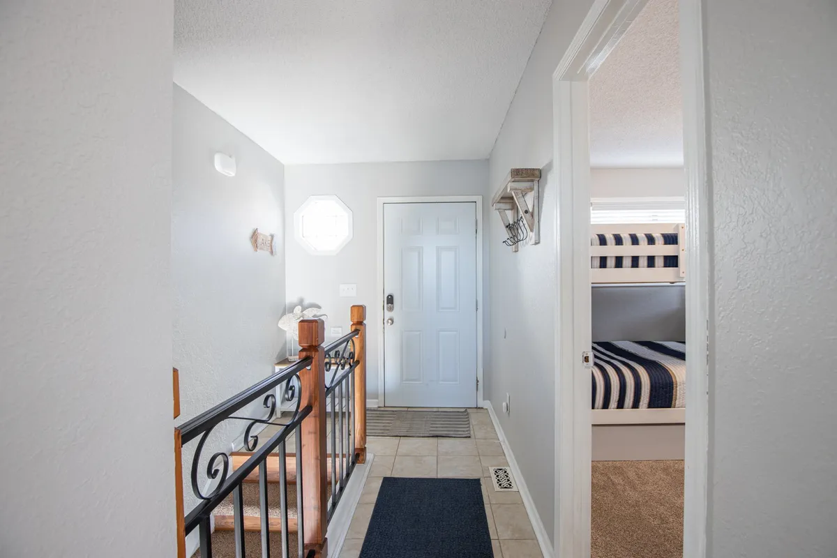 A welcoming interior space featuring a staircase, front door, and built-in full-over-full bunk beds. The area is styled for family gatherings and quiet moments, making it ideal for flexible sleeping arrangements.