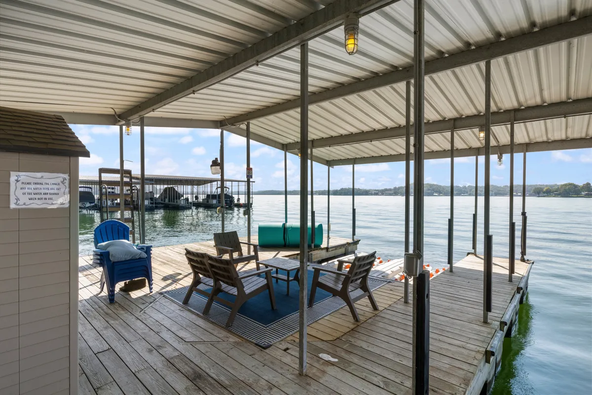 A wooden dock equipped with lounge chairs overlooks the serene water and blue sky, inviting guests to relax, fish, socialize, or enjoy morning coffee right by the lake.