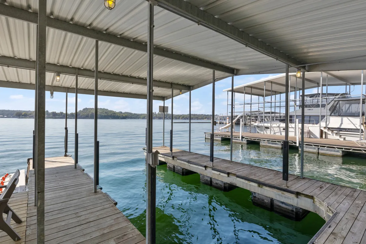 This image captures a spacious dock extending out over calm lake waters, with boats visible and a scenic shoreline in the background. The tranquil setting invites activities such as boating, fishing, and relaxing by the water—core experiences highlighted in the section.